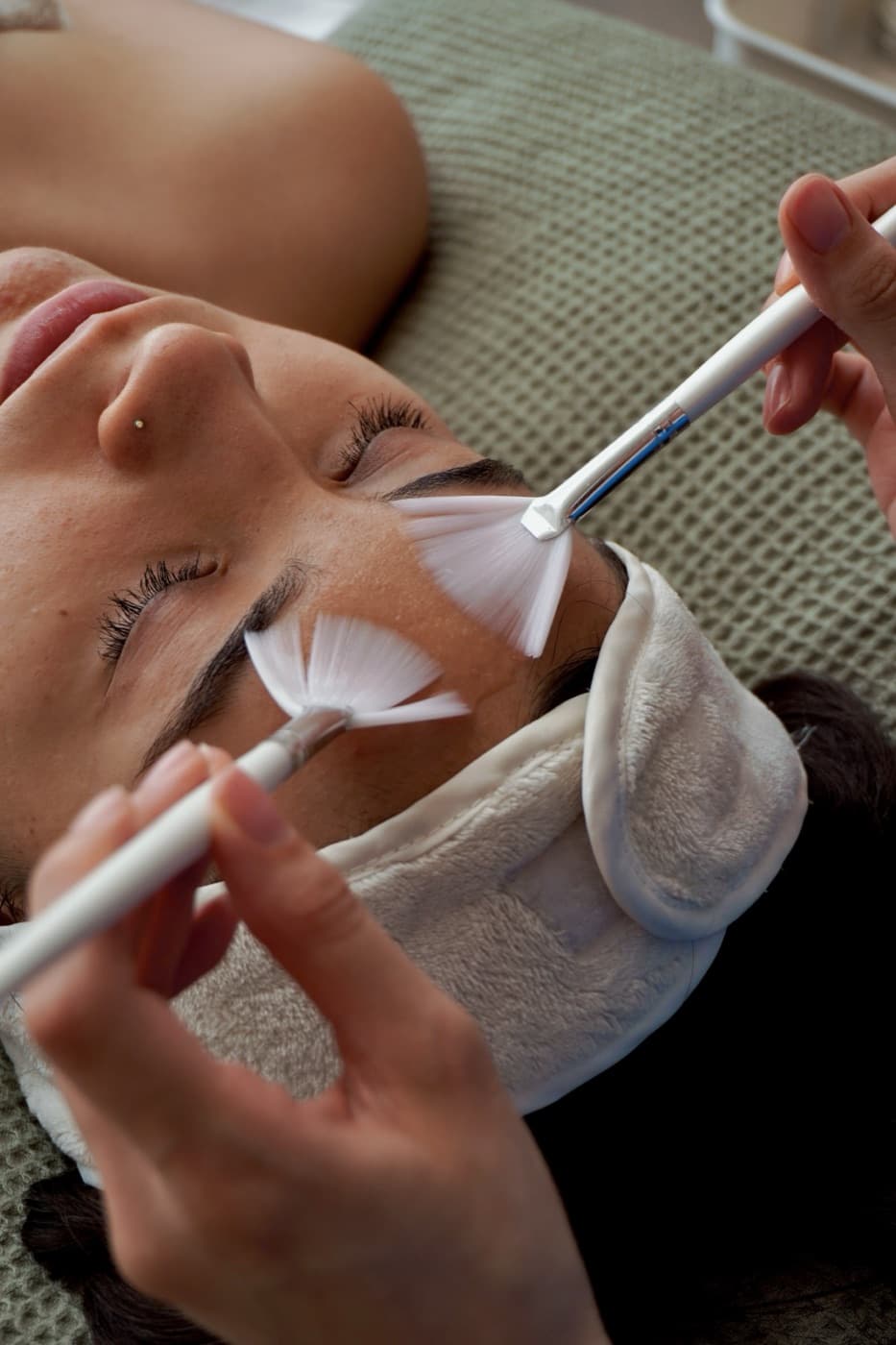Aplicación de tratamiento facial con brochas de abanico